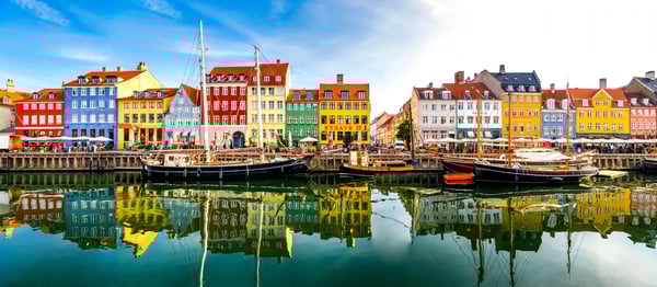 Bunte Häuser und historische Segelboote spiegeln sich im Hafen von Nyhavn in Kopenhagen