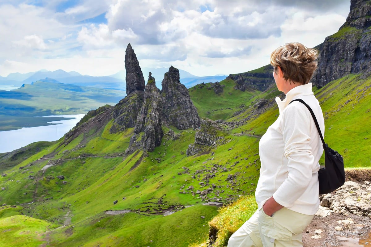Person blickt auf markante Felsformationen auf der Isle of Skye in weiter Landschaft