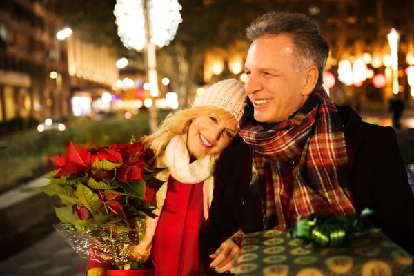 Paar mit Geschenk und Blumen in festlich beleuchteter Strasse bei Nacht