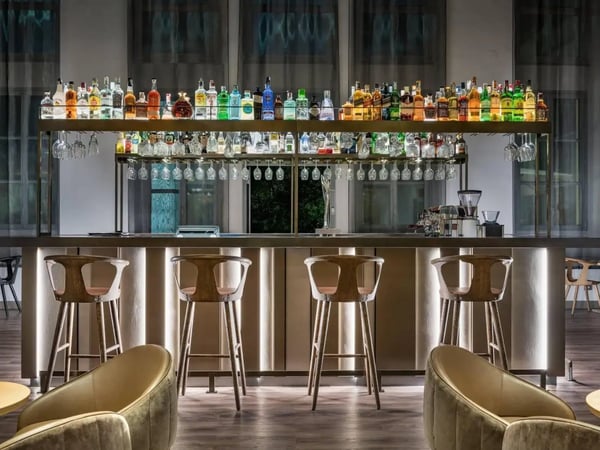 Moderne Hotelbar mit beleuchteten Regalen, vielen Flaschen und Barhockern
