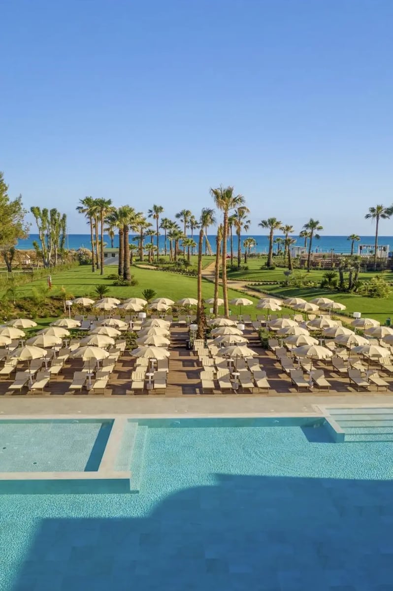 Weitläufige Poolanlage mit Liegen, Palmen und Blick auf das Meer bei Cefalu