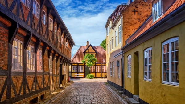 Historische Gasse mit farbigen Fachwerkhäusern und Kopfsteinpflaster in der Altstadt von Ribe in Dänemark unter blauem Himmel