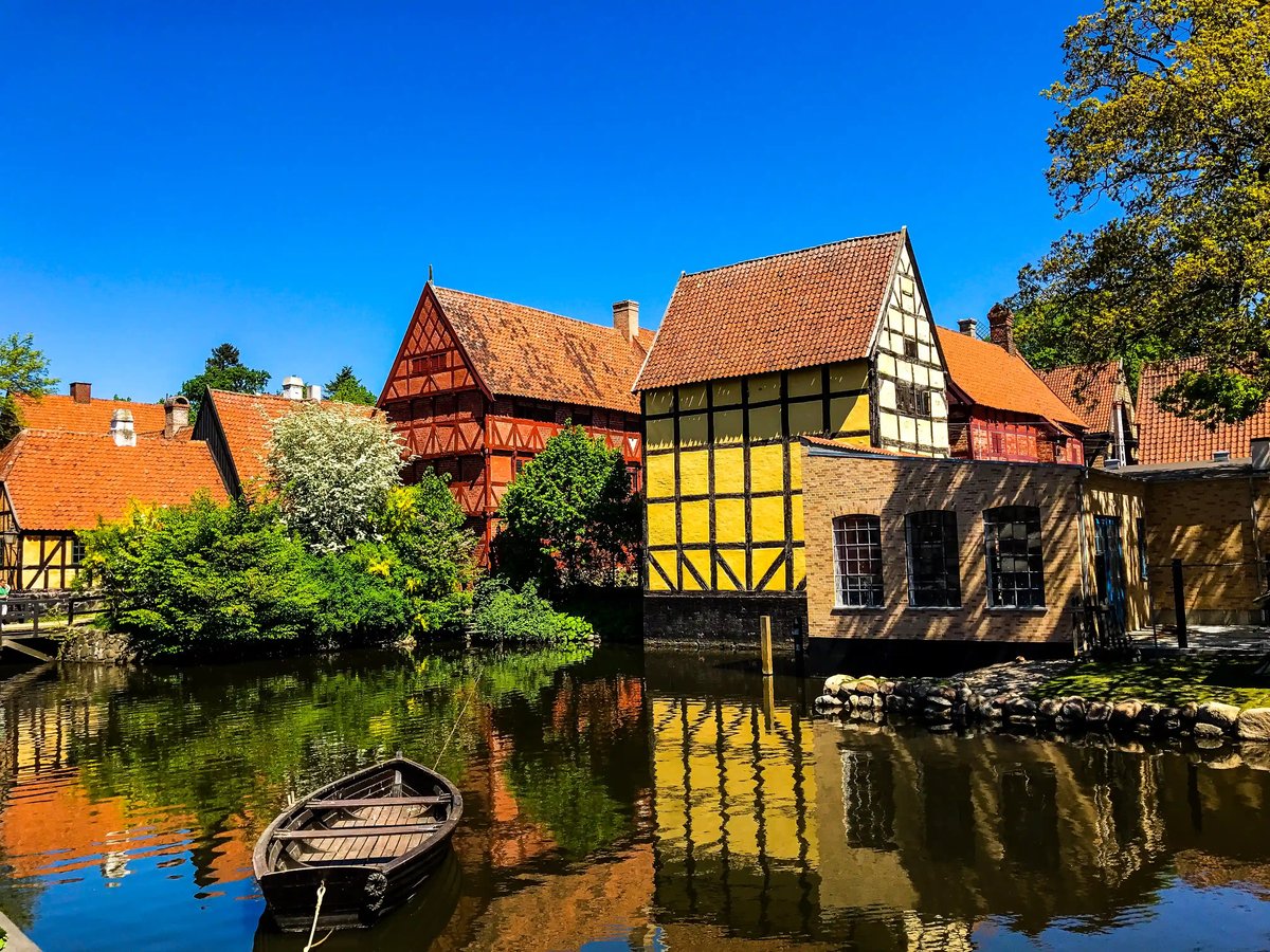 Historische Fachwerkhäuser am Wasser mit gelber Fassade und Spiegelung im Kanal unter blauem Himmel