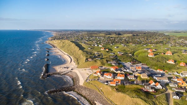 Luftaufnahme einer dänischen Küstenlandschaft mit Steilküste Strand und verstreuten Häusern
