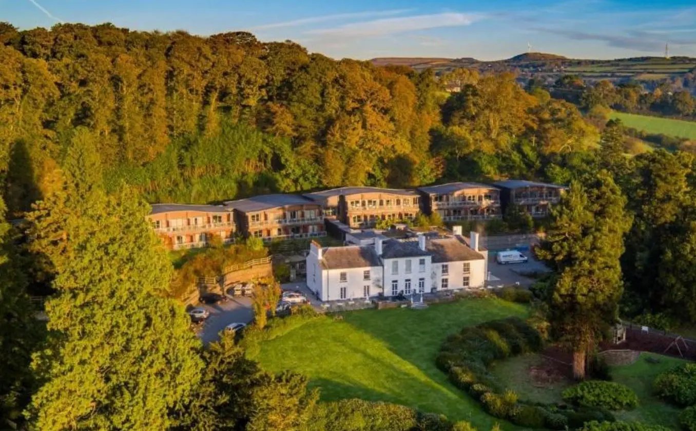 Hotelanlage inmitten einer grünen Parklandschaft mit Haupthaus und modernen Gästezimmern