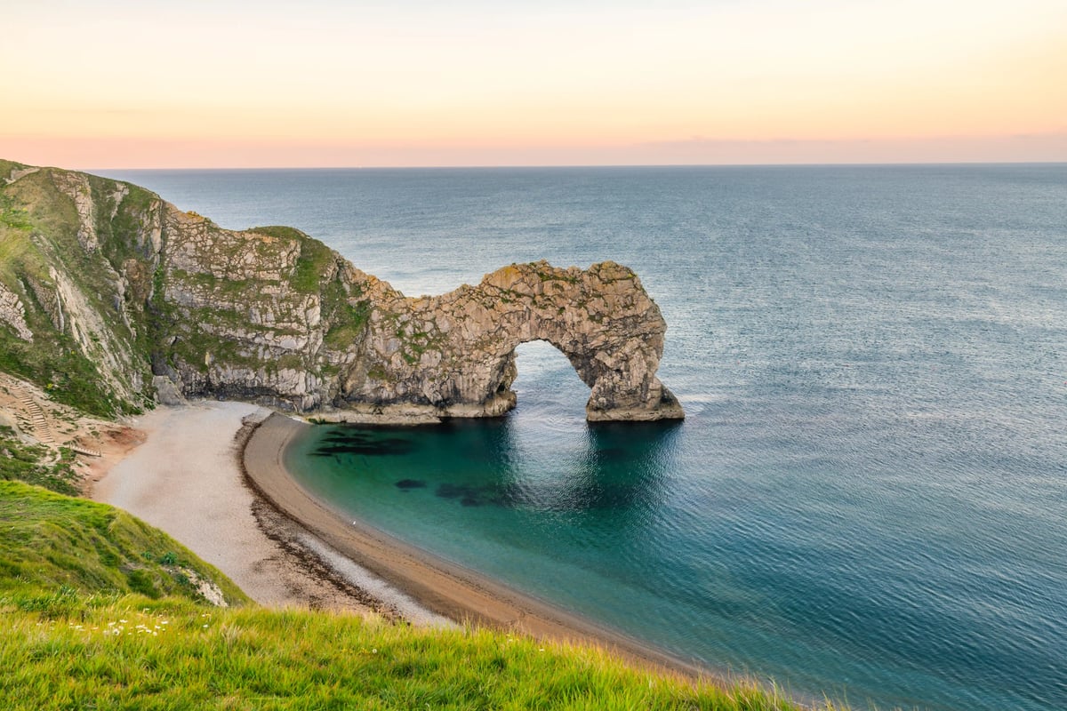 Felsentor Durdle Door an der Jurassic Coast mit Sandstrand und türkisblauem Meer