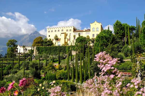 Schloss Trauttmansdorff mit Terrassengärten, Zypressen und Bergen im Hintergrund