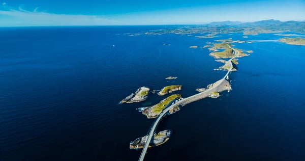Luftaufnahme der Atlantikstrasse mit geschwungener Brücke über Inseln und offenes Meer