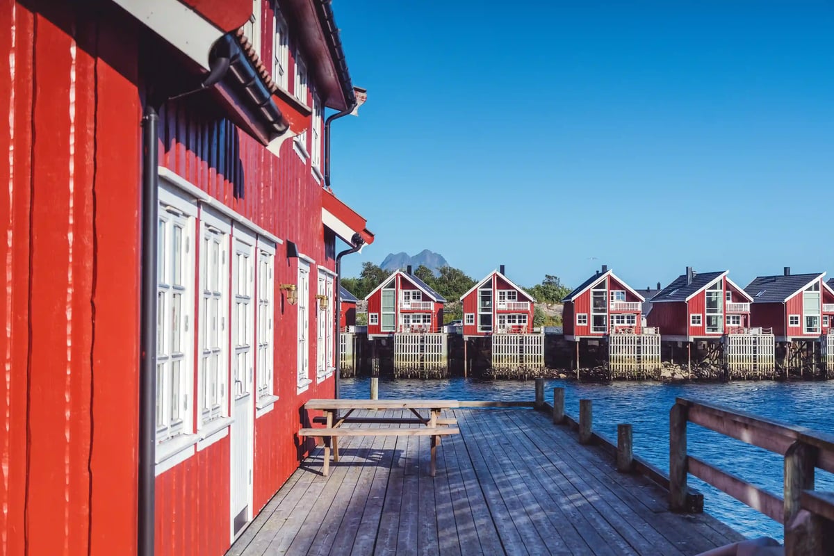 Rote Holzhäuser am Wasser in Svolvaer auf den Lofoten mit Holzsteg im Vordergrund