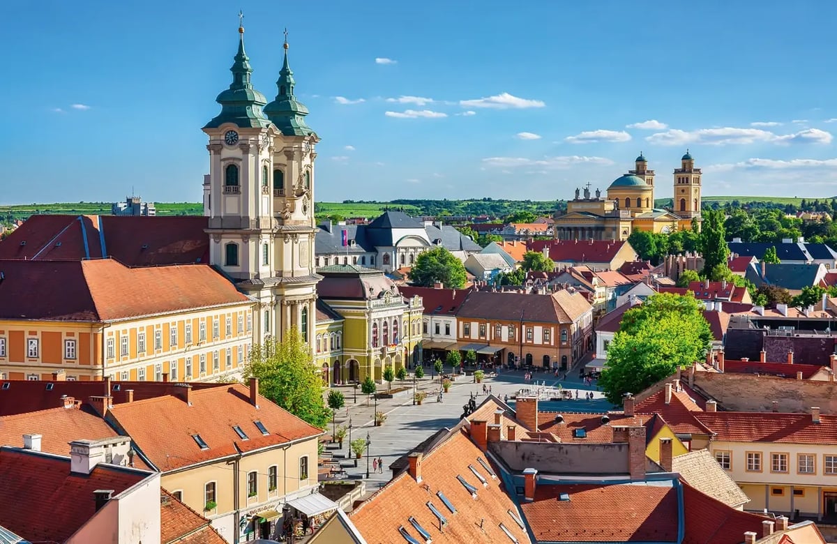 Panoramablick über die historische Altstadt von Eger mit barocken Kirchen und roten Ziegeldächern.