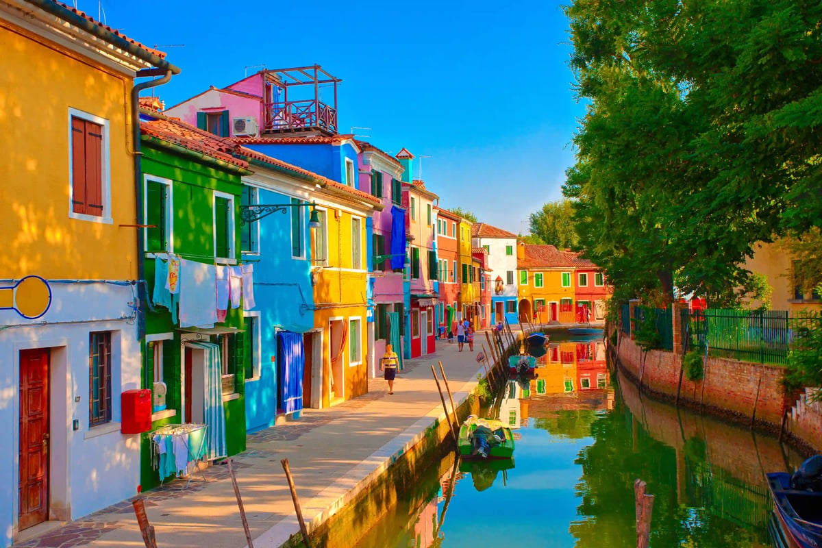 Bunte Häuser entlang eines Kanals auf der Insel Burano mit Spiegelungen im Wasser