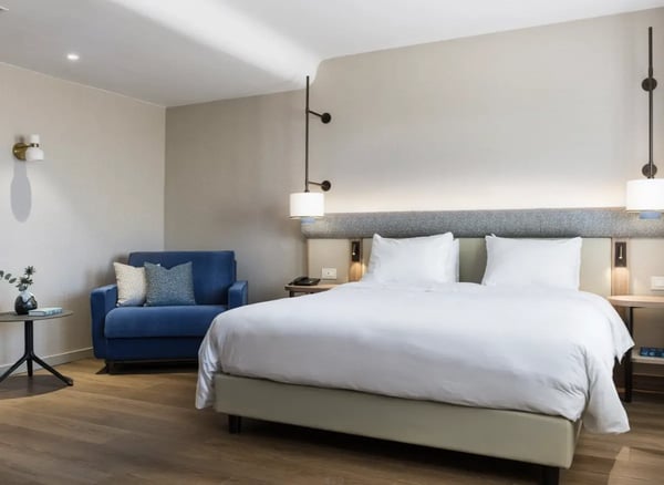 Modernes Hotelzimmer mit Doppelbett, Sitzmöbel, Holzboden und warmem Licht