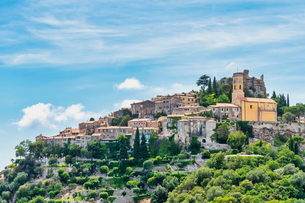 Village médiéval de Eze perché sur une colline verdoyante avec maisons en pierre et église sous ciel bleu