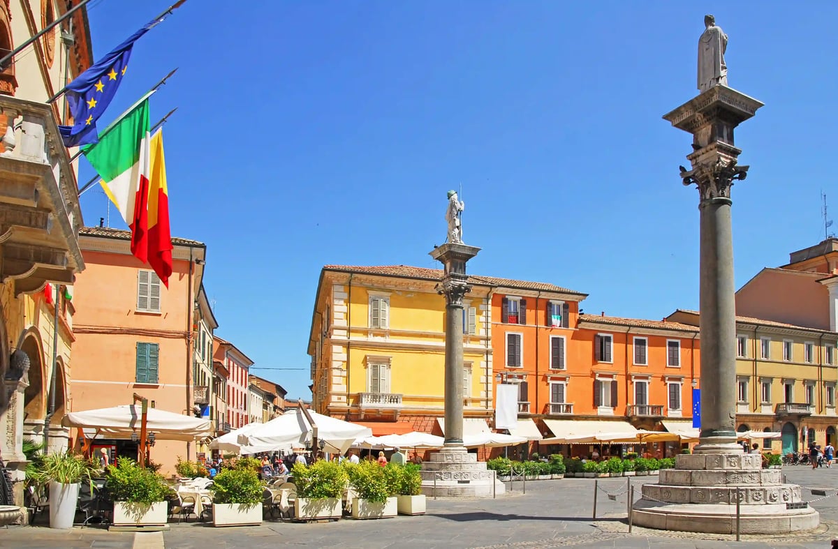 Place historique de Ravenne avec colonnes, cafés, drapeaux et bâtiments colorés