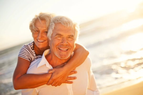 Couple âgé s’enlaçant sur la plage dans la lumière dorée du coucher du soleil