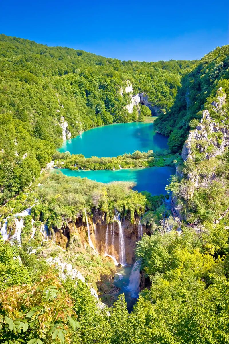 Mehrstufige Wasserfälle und klare Seen im Plitvicer Nationalpark, eingebettet in dichten Wald