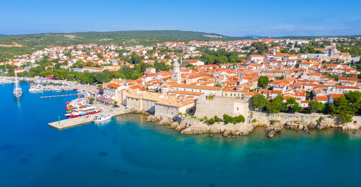 Luftaufnahme der Insel Krk mit Hafen, Altstadt und türkisfarbenem Wasser