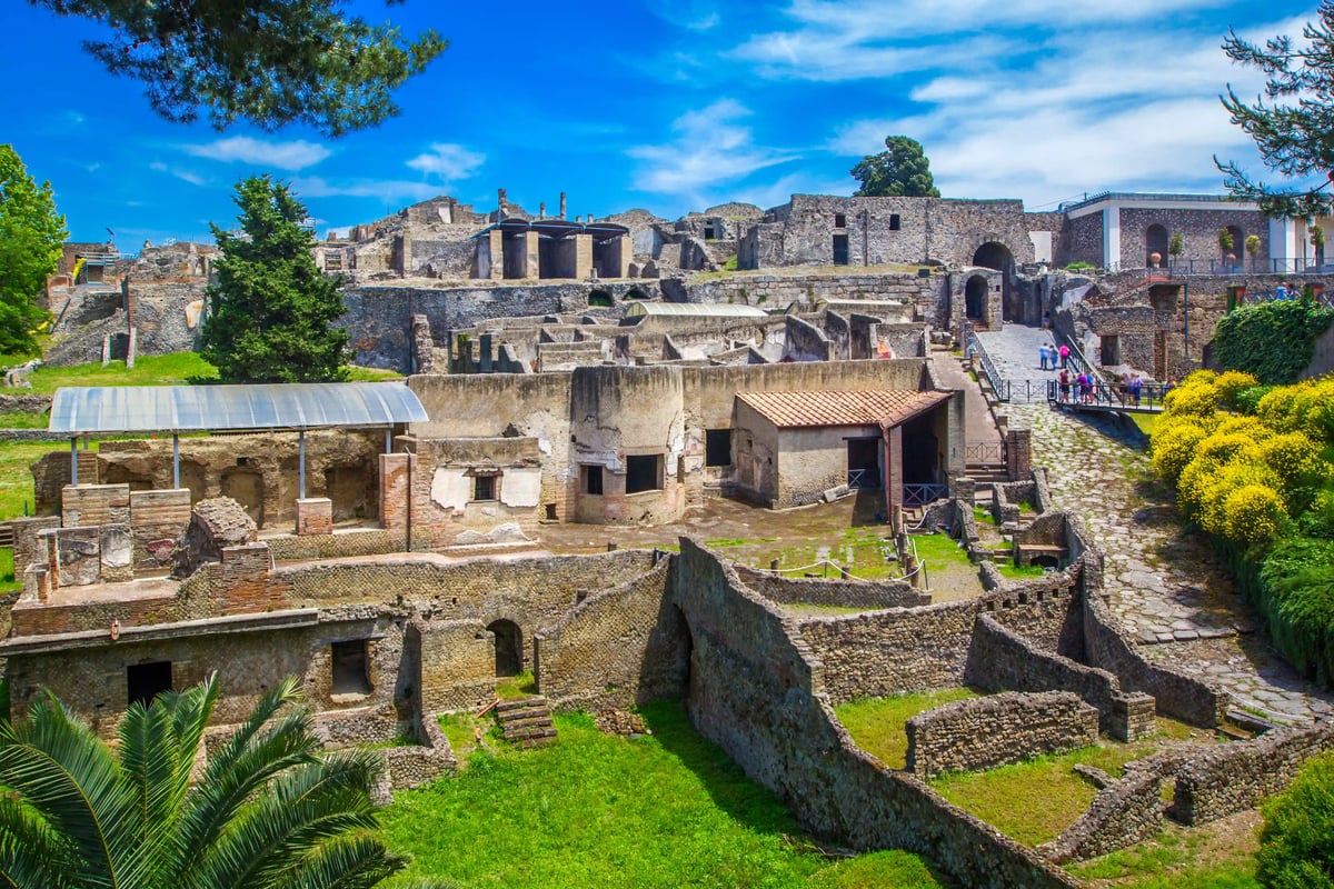 Weitläufige Ruinen der antiken Stadt Pompeji mit erhaltenen Mauern, Wegen und Gebäuderesten unter blauem Himmel