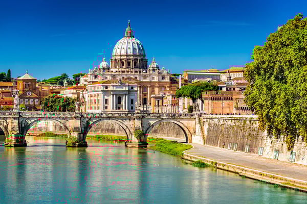 Blick auf den Petersdom in Rom mit Kuppel, Brücke über den Tiber und historischer Stadtarchitektur