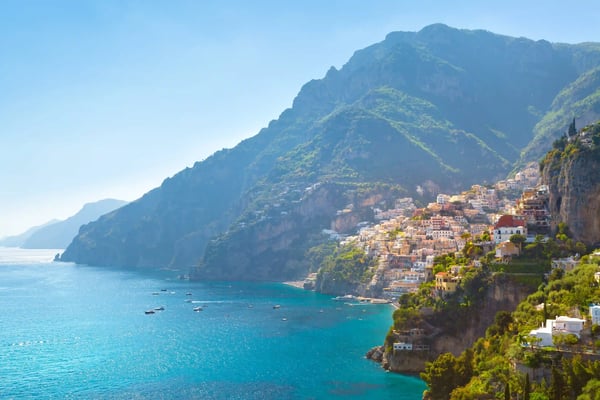 Küstenstadt an der Amalfiküste mit bunten Häusern am Hang, türkisblauem Meer und steilen Bergen