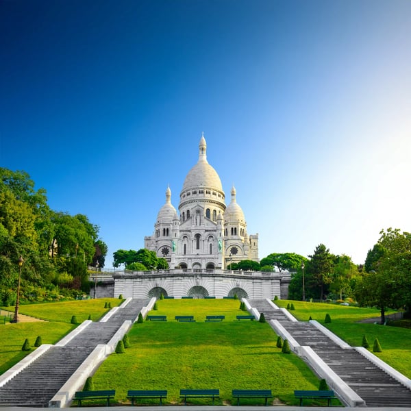Basilika Sacre Coeur auf dem Montmartre mit breiten Treppen und Grünflächen im Vordergrund