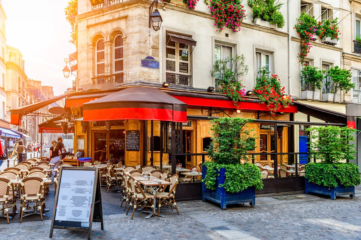 Typisches Pariser Strassencafé mit roten Markisen, gedeckten Tischen und bepflanzter Hausfassade