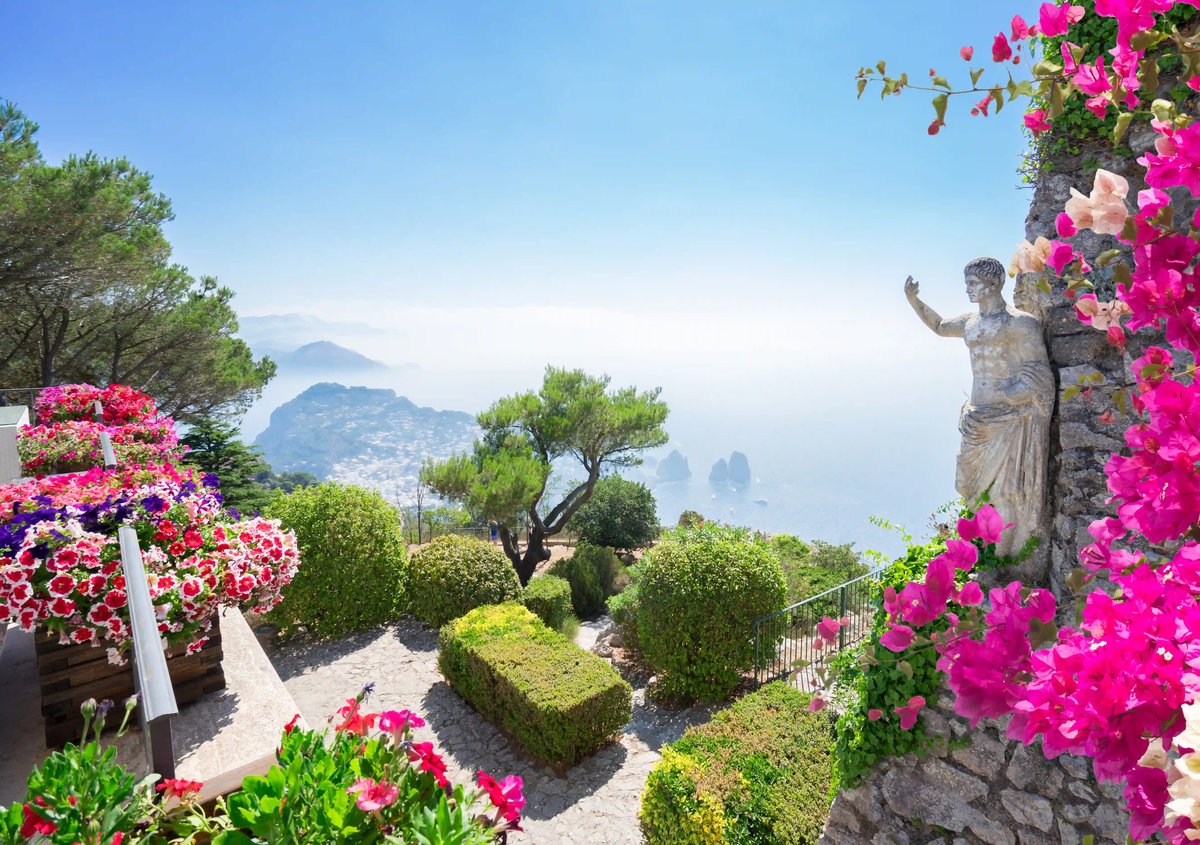 Jardin avec fleurs colorees, statue et large vue sur la mer et la cote de Capri