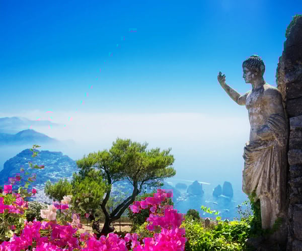Antike Statue in einem Garten mit Blumen und Blick auf das Meer und die Felsen von Capri