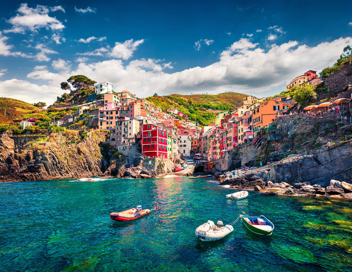 Küstenlandschaft der Cinque Terre mit bunten Häusern Felsen und Booten im klaren Wasser