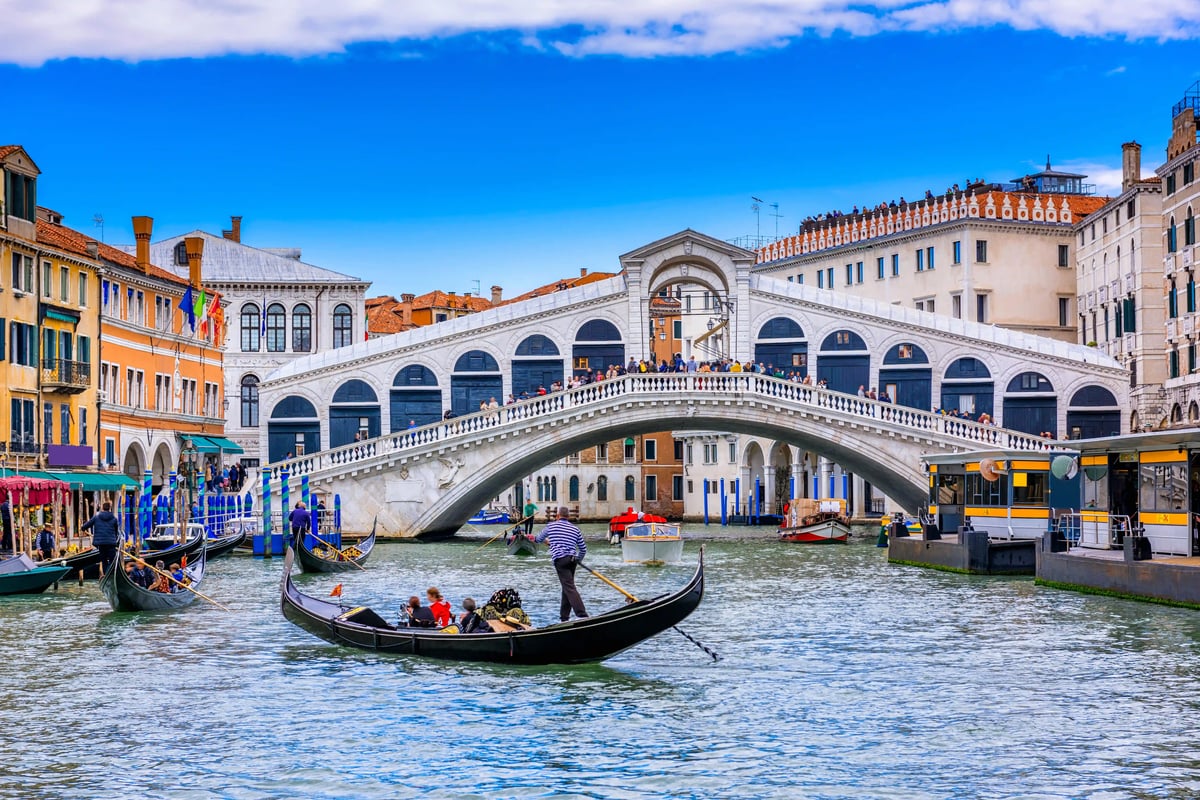 Rialtobrücke in Venedig mit Gondeln auf dem Canal Grande und zahlreichen Besuchern