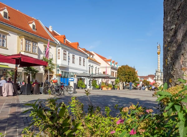 Fussgängerzone in Eisenstadt mit historischen Häusern, Cafés und bepflanztem Platz