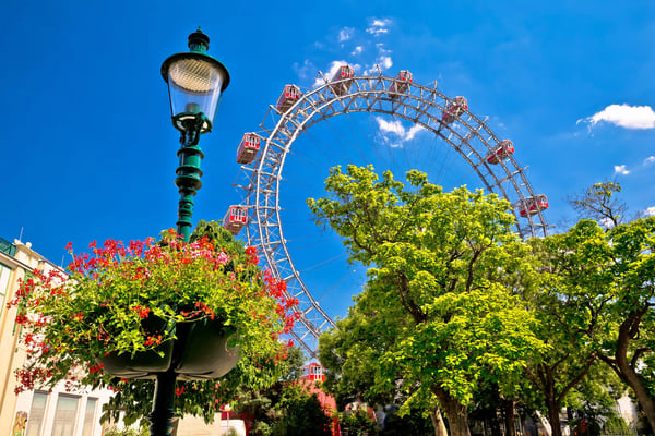 Riesenrad im Wiener Prater zwischen Bäumen, Laterne und blauem Himmel
