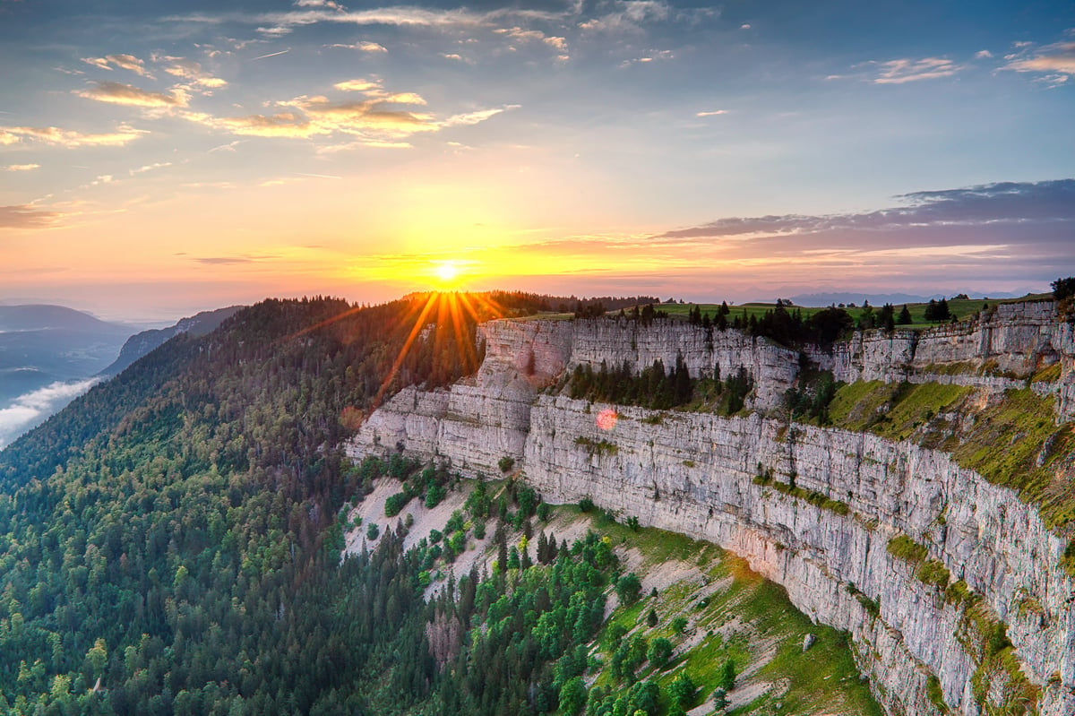Sonnenuntergang über steilen Felswänden und bewaldeten Hängen am Creux du Van