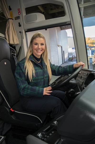 Beatrice Egli sitzt am Steuer eines modernen Reisebusses und blickt in die Kamera