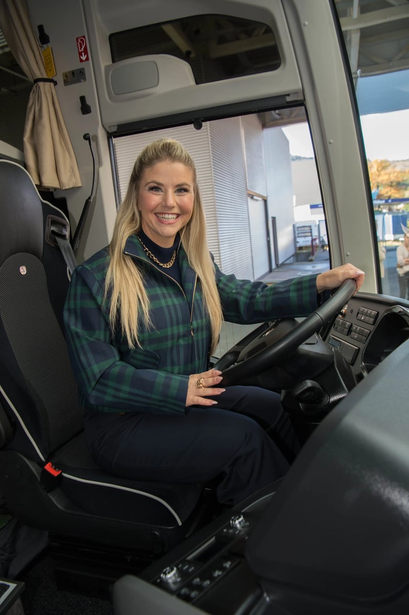 Beatrice Egli sitzt am Steuer eines modernen Reisebusses und blickt in die Kamera
