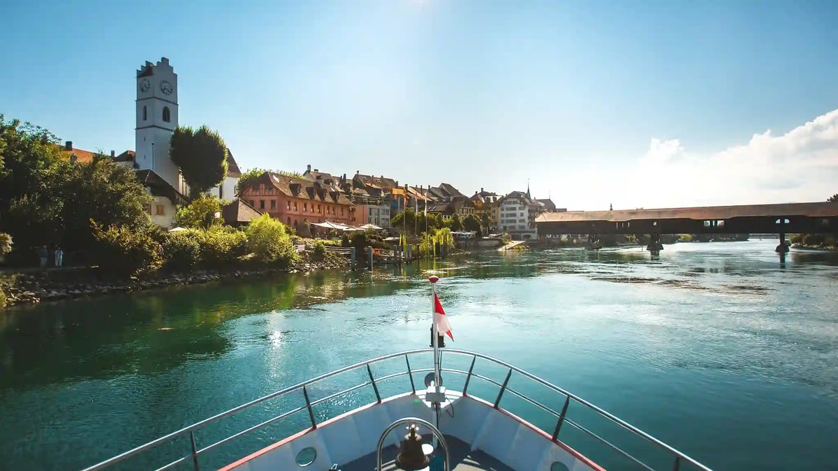Blick vom Bug eines Schiffes auf die Aare mit Altstadt, Kirche und überdachter Brücke