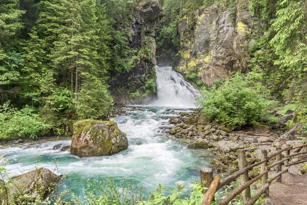 Tosender Wasserfall stürzt durch bewaldete Schlucht in klares türkisfarbenes Wasser