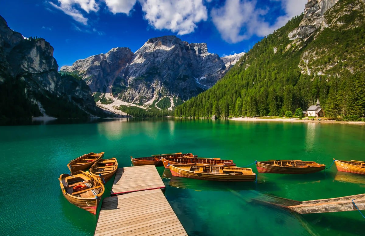 Türkisfarbener Pragser Wildsee mit Holzbooten vor alpiner Bergkulisse