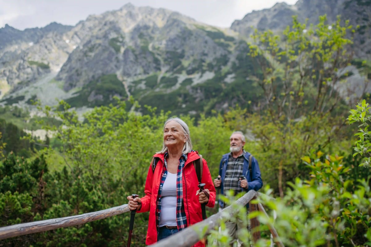 Wanderndes Paar auf Holzsteg mit Berglandschaft im Hintergrund