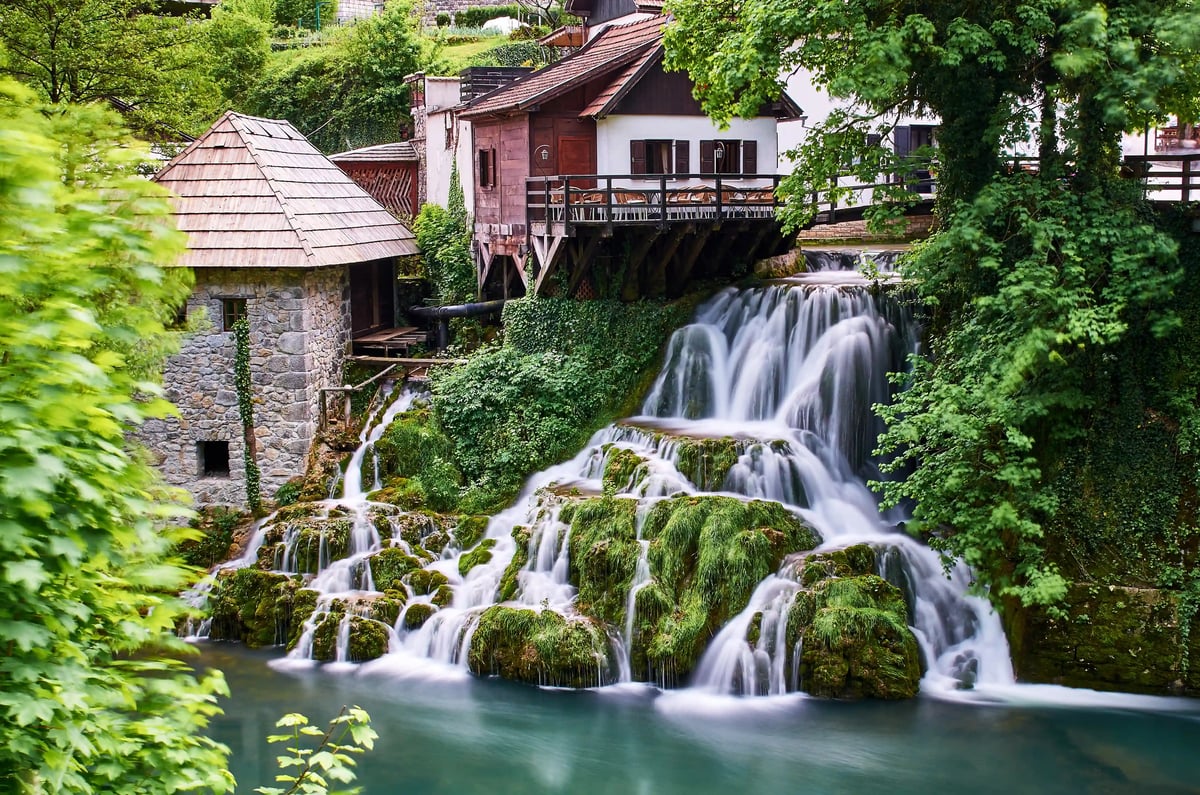 Wasserfälle von Rastoke mit historischen Häusern, Moosfelsen und fliessendem Wasser in grüner Umgebung