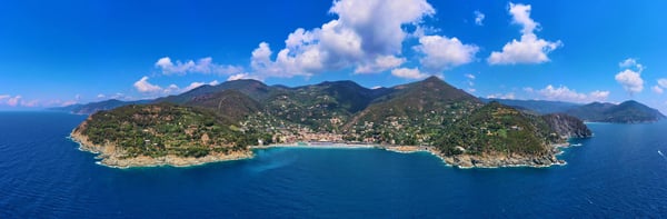 Panoramablick auf eine grüne Küstenlandschaft mit Bergen, Buchten und blauem Meer in Ligurien