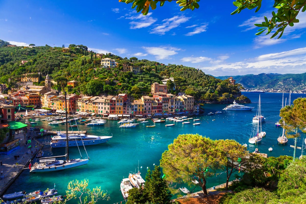 Blick auf den Hafen von Portofino mit bunten Häusern, Yachten, grünen Hügeln und türkisfarbenem Wasser