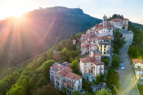 Village aux toits de tuiles s’étire sur un versant, lumière dorée sur des collines boisées.