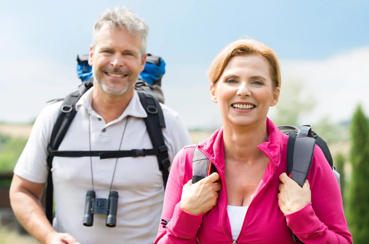 Fröhliches Paar beim Wandern mit Rucksack in grüner Landschaft