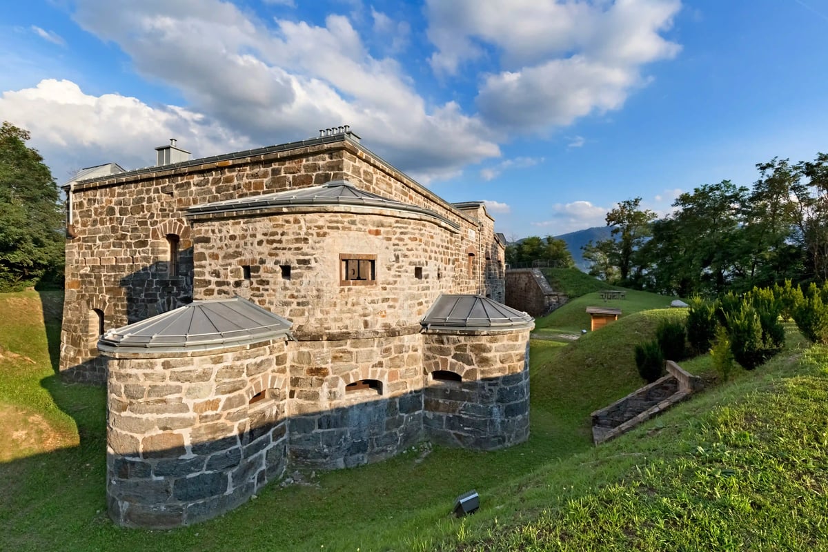 Forteresse historique en pierre naturelle dans un parc verdoyant avec collines et arbres