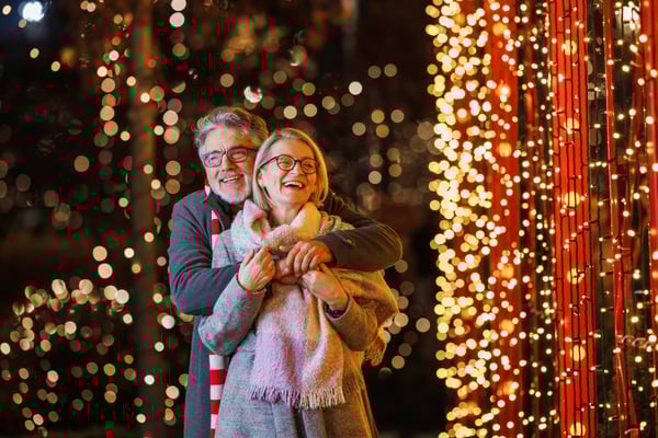 Fröhliches Paar vor funkelnder Weihnachtsbeleuchtung