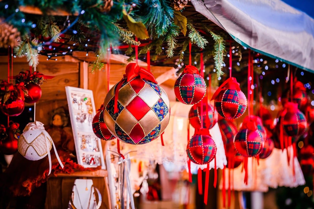 Bunte Weihnachtskugeln hängen an einem Marktstand