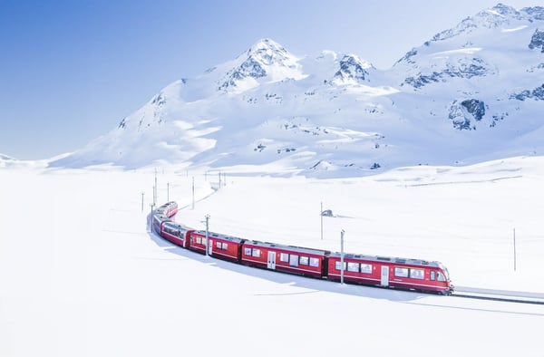 Bernina Express fährt durch eine weite verschneite Berglandschaft