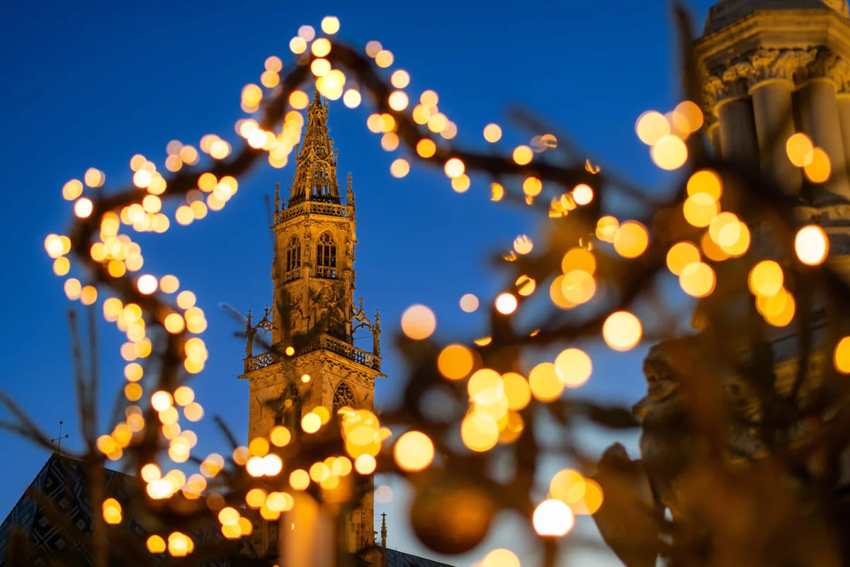 Kirchturm hinter unscharfen Lichtern auf einem Weihnachtsmarkt