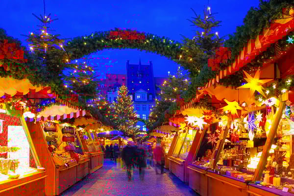 Weihnachtsmarkt mit beleuchteten Ständen und dekoriertem Torbogen